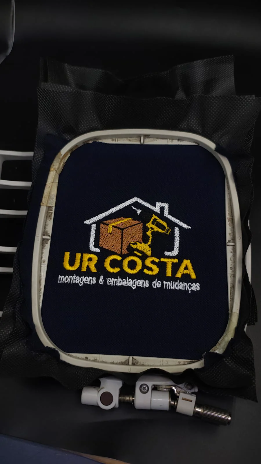 Bordado do logotipo UR Costa em tecido preto